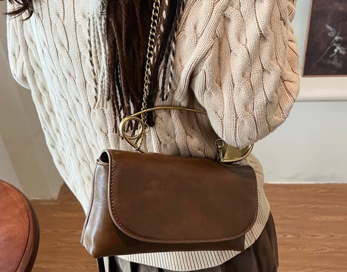 Person wearing a brown leather handbag with a neutral background