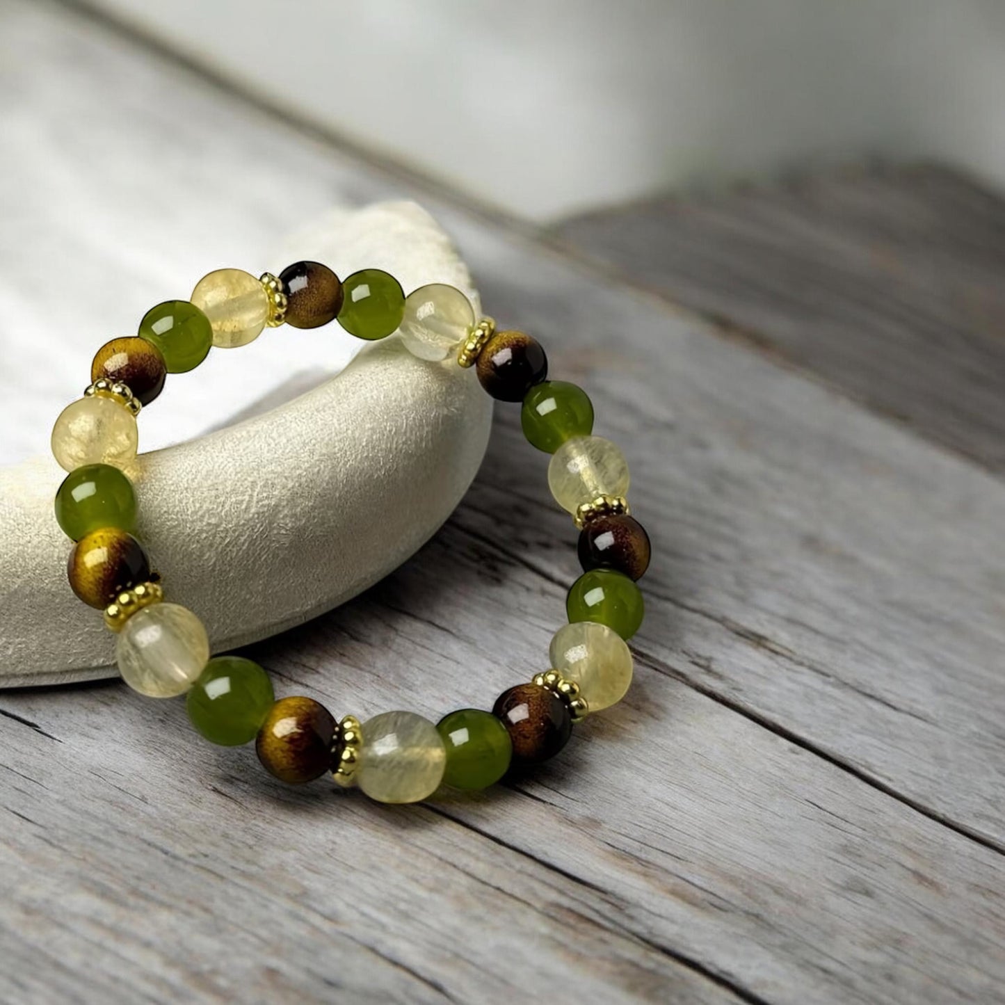 Beaded bracelet with green and brown stones on a wooden surface