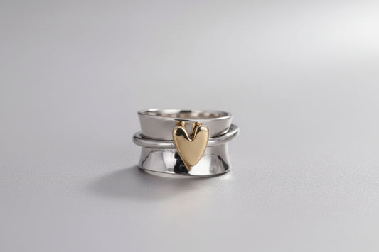 Silver ring with a gold heart-shaped center held by a hand, with measurements indicated.