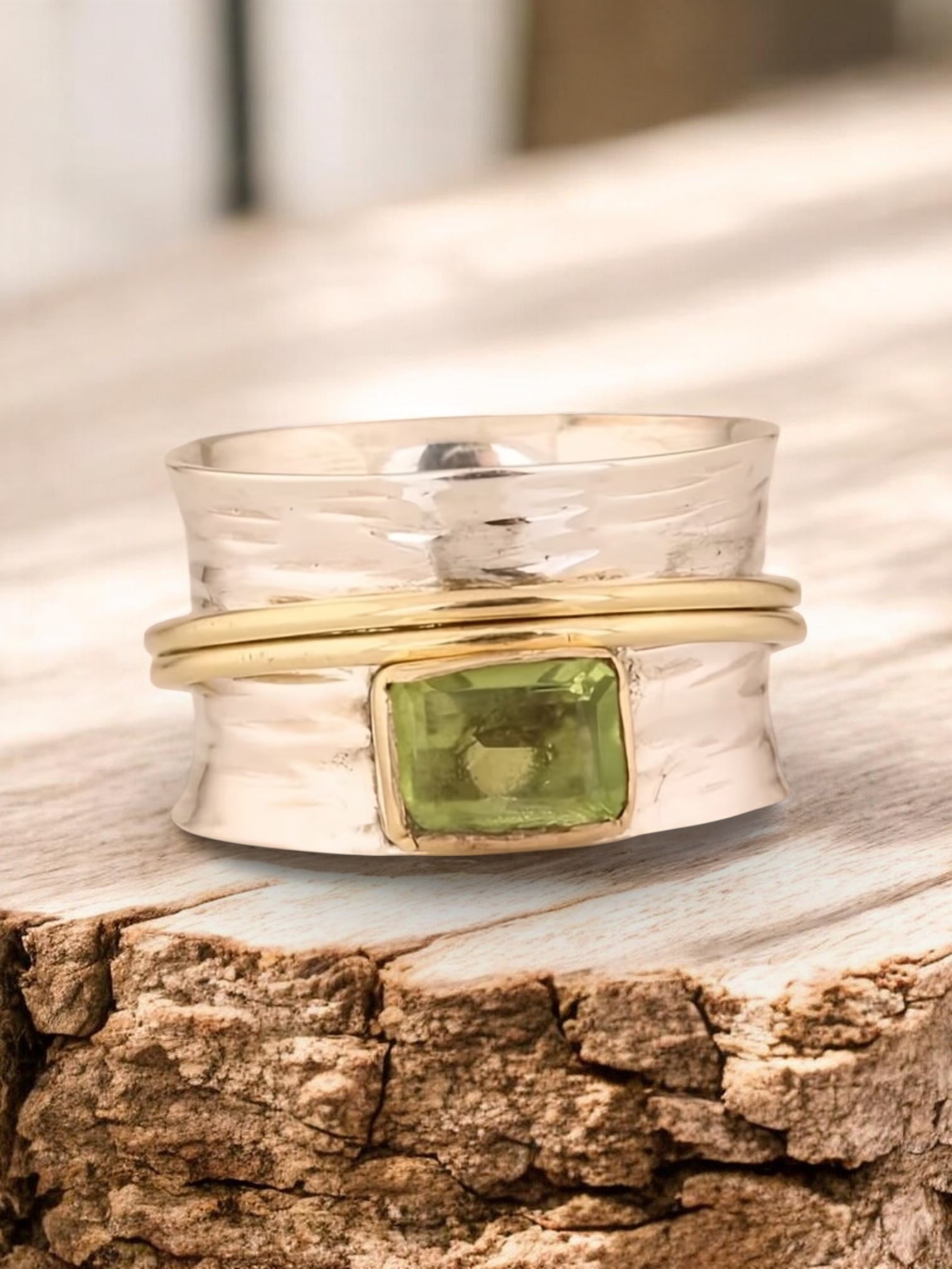 Silver ring with a green gemstone on a wooden surface