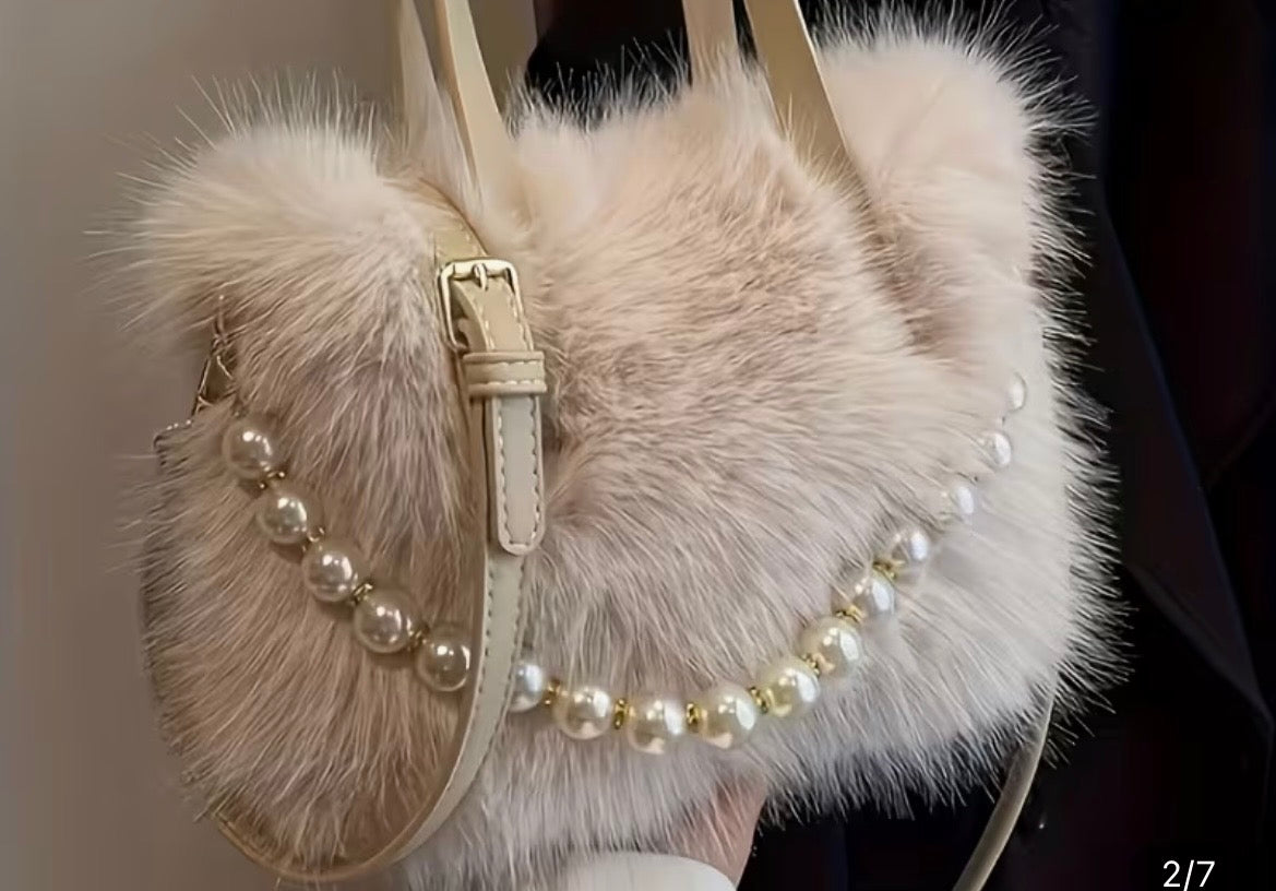 Furry handbag with pearl embellishments on a neutral background