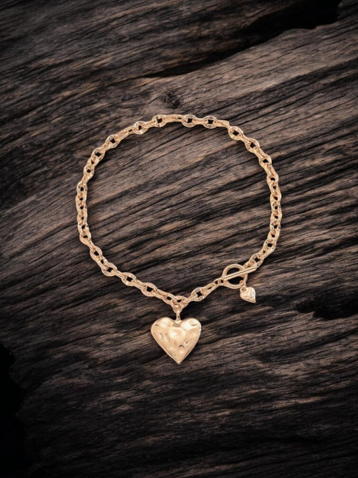 Gold necklace with a heart-shaped charm on a wooden surface
