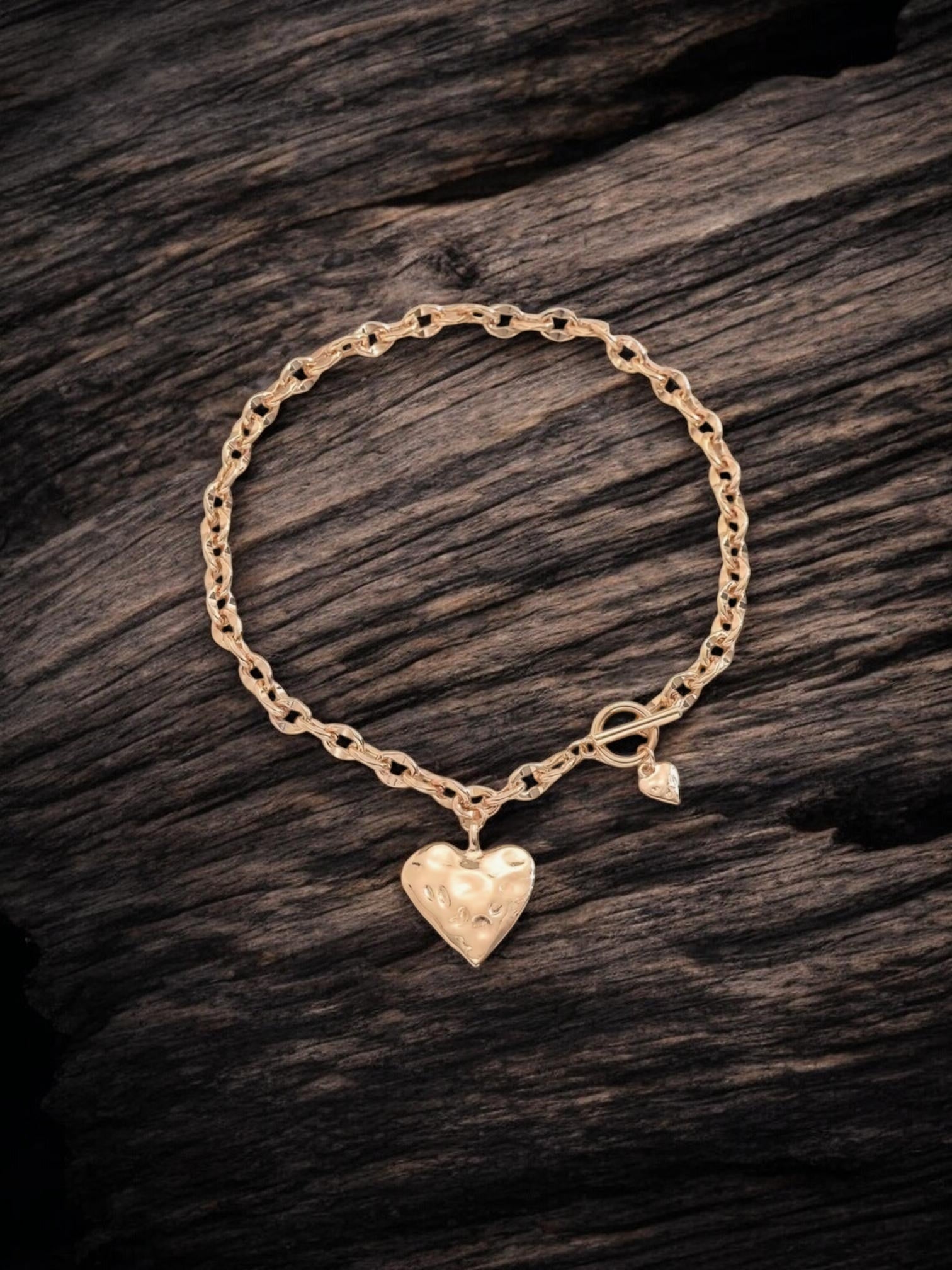 Gold necklace with a heart-shaped charm on a wooden surface