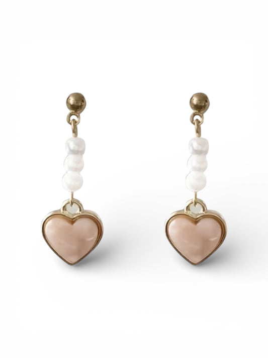 Heart-shaped earrings with beige heart charms and white beads on a white background