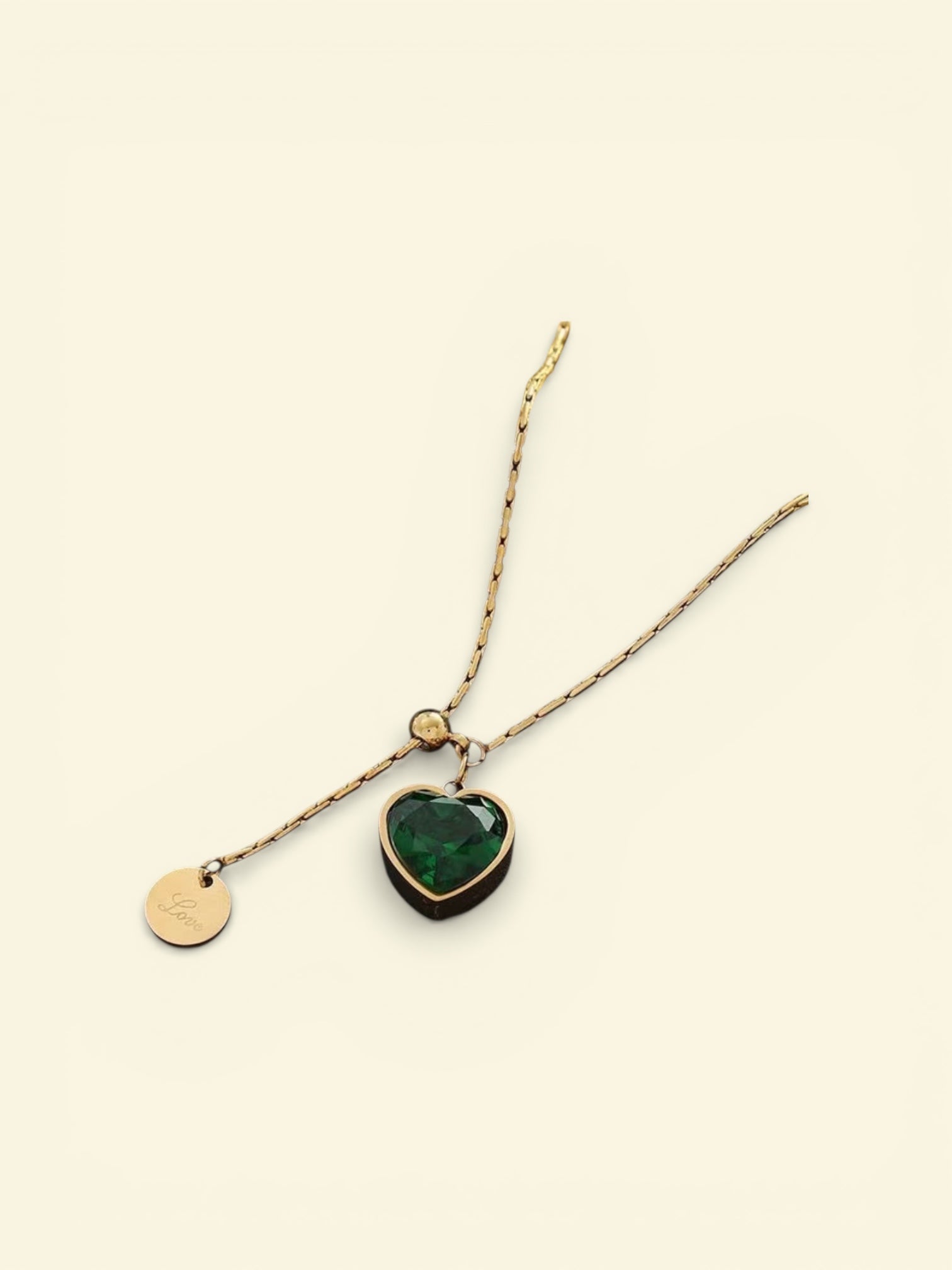 Necklace with a heart-shaped green pendant on a beige background
