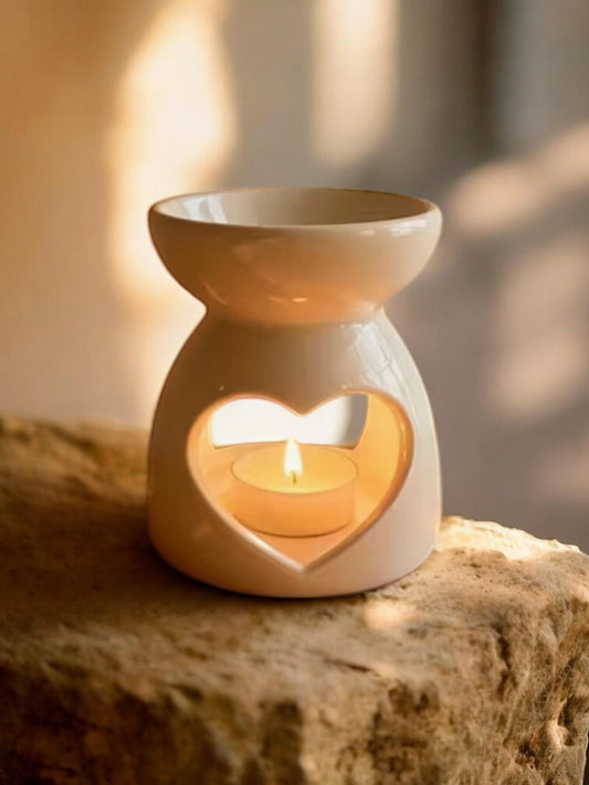 Ceramic oil burner with heart-shaped cutout on a stone surface