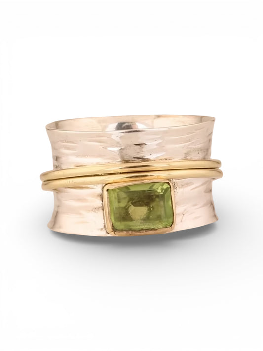 Gold and silver ring with a green gemstone on a white background