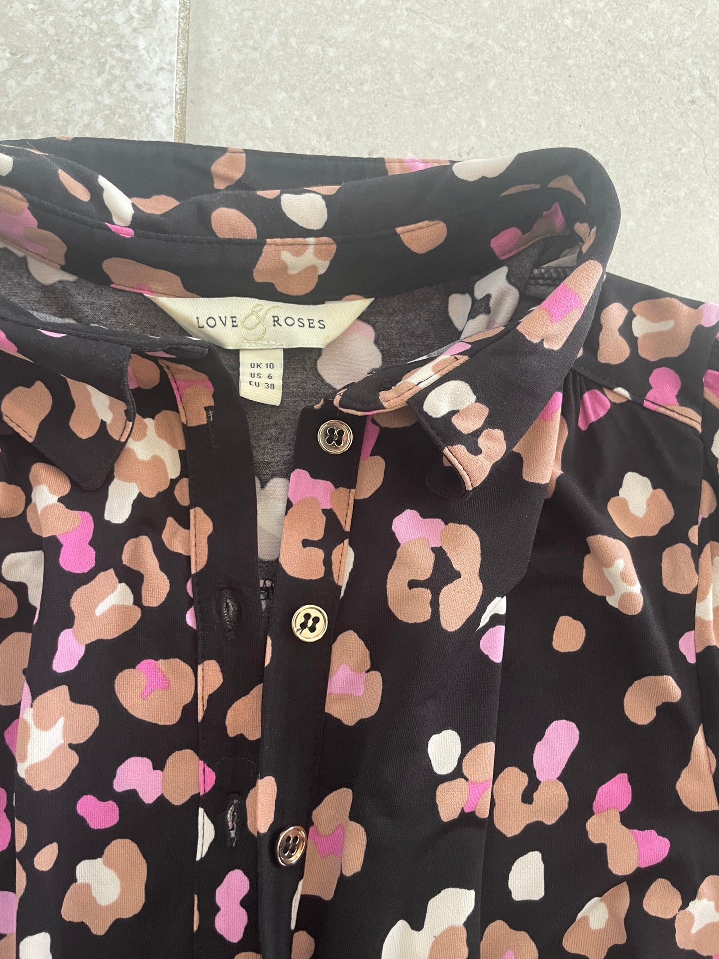 Black shirt with pink and beige abstract pattern on a textured surface