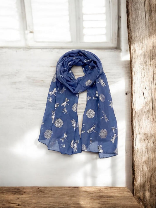 Blue floral patterned scarf draped over a wooden surface with a white wall background