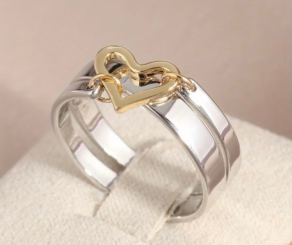 Two-toned ring with gold heart-shaped design on a beige background