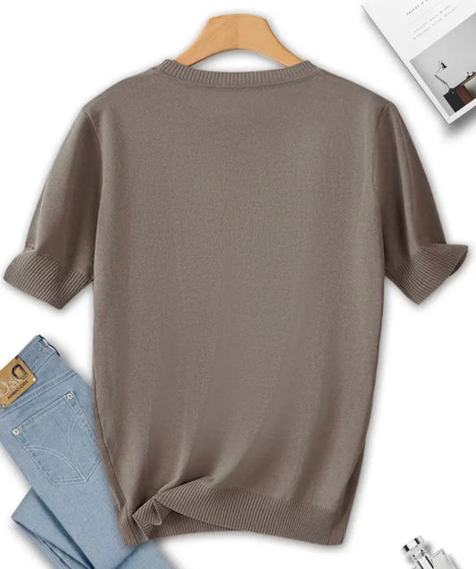 Brown sweater on a hanger with jeans and a magazine in the background