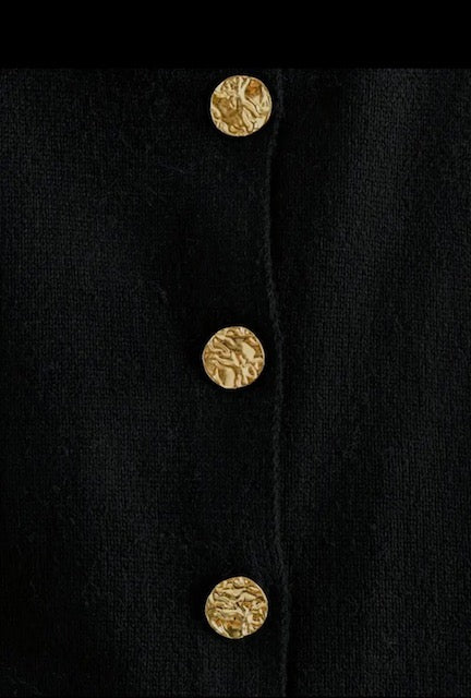 Close-up of a black coat with gold buttons on a black background