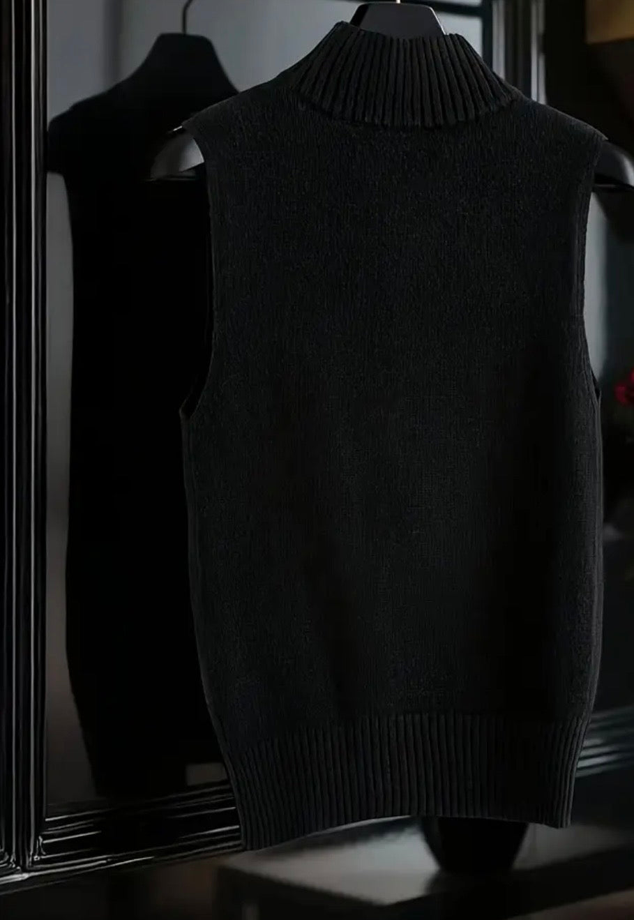 Dark black sweater vest on a hanger against a dark background