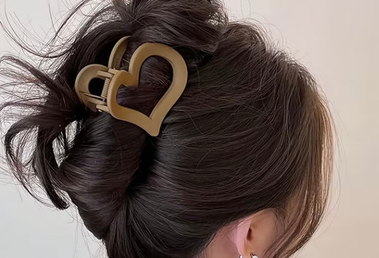 Close-up of a hair bun with a heart-shaped hair clip on a neutral background