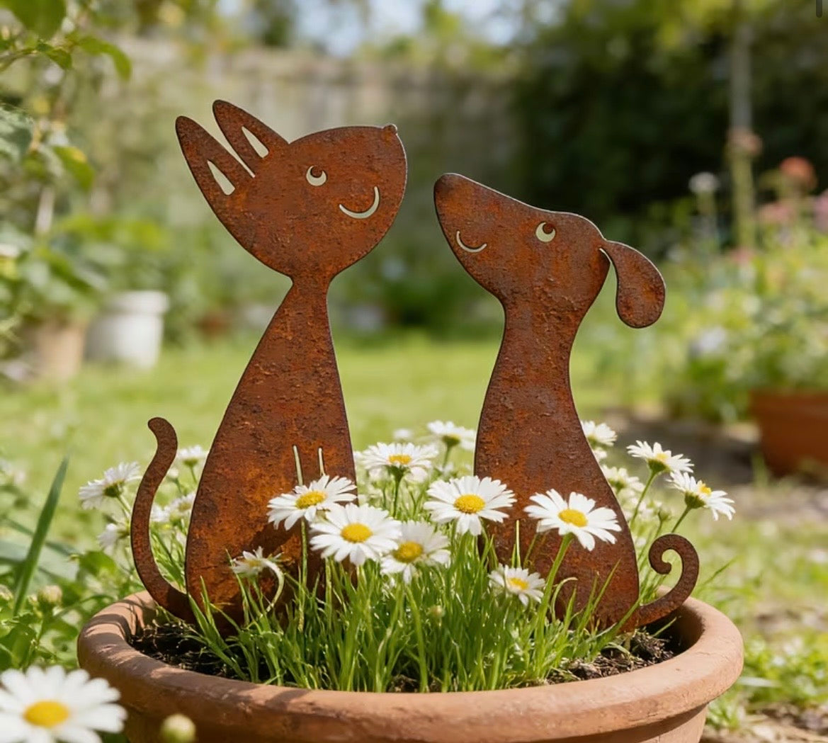 Rust-colored metal cat and dog sculptures in a pot with flowers
