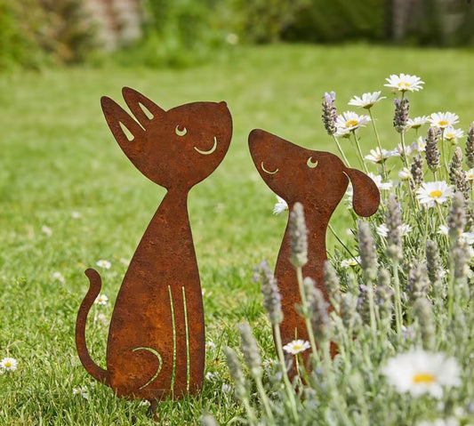 Metallic cat and dog sculptures in a garden with flowers