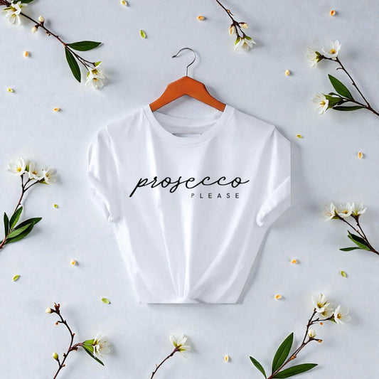 White t-shirt with 'prosecco please' text on a hanger surrounded by flowers on a light background