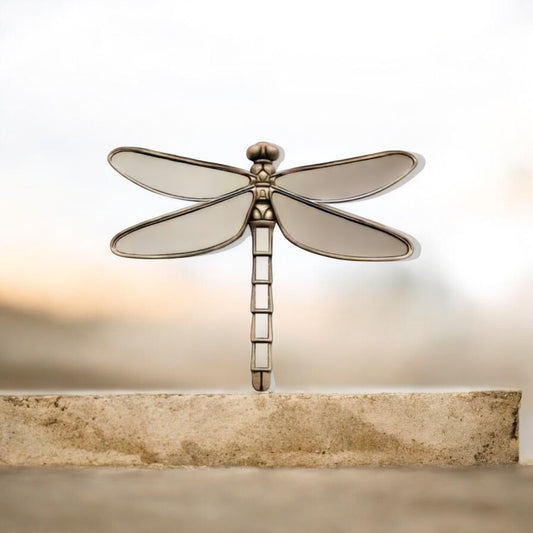 Decorative dragonfly-shaped mirror on a stone surface with a soft light background