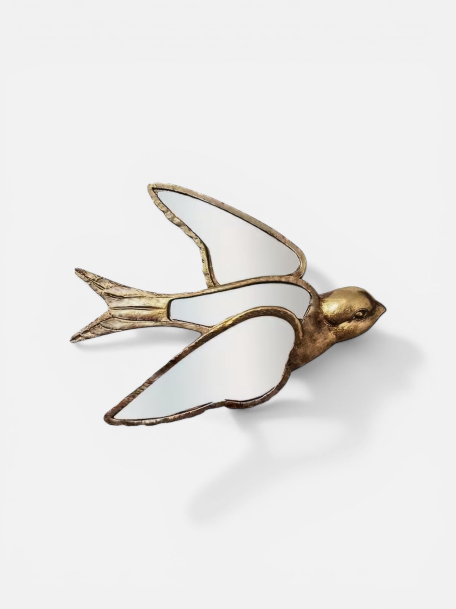Decorative bird-shaped mirror with gold and white design on a light gray background