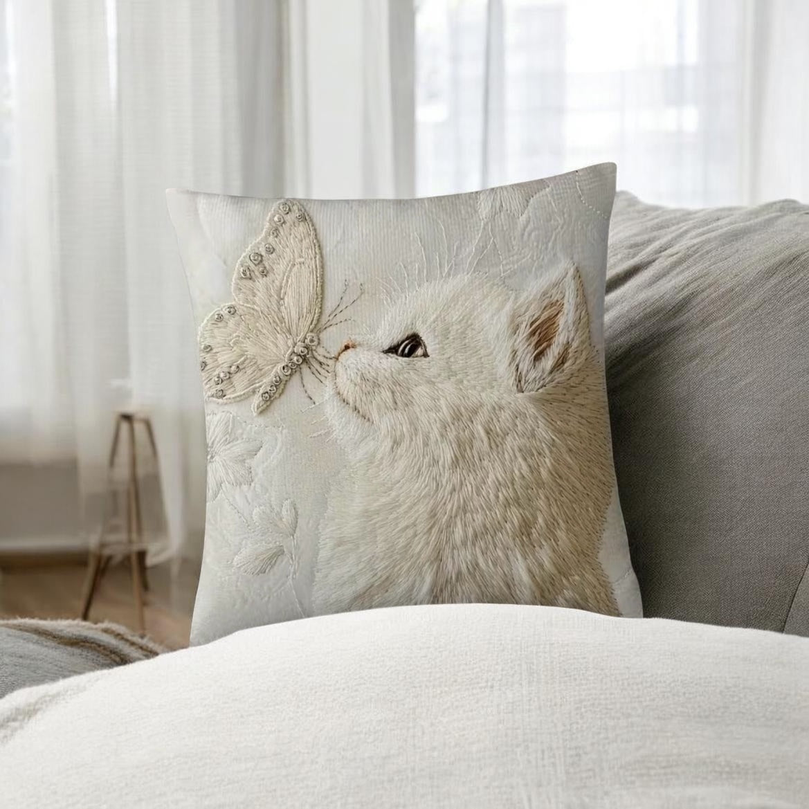 Decorative pillow with a cat and butterfly design on a couch.