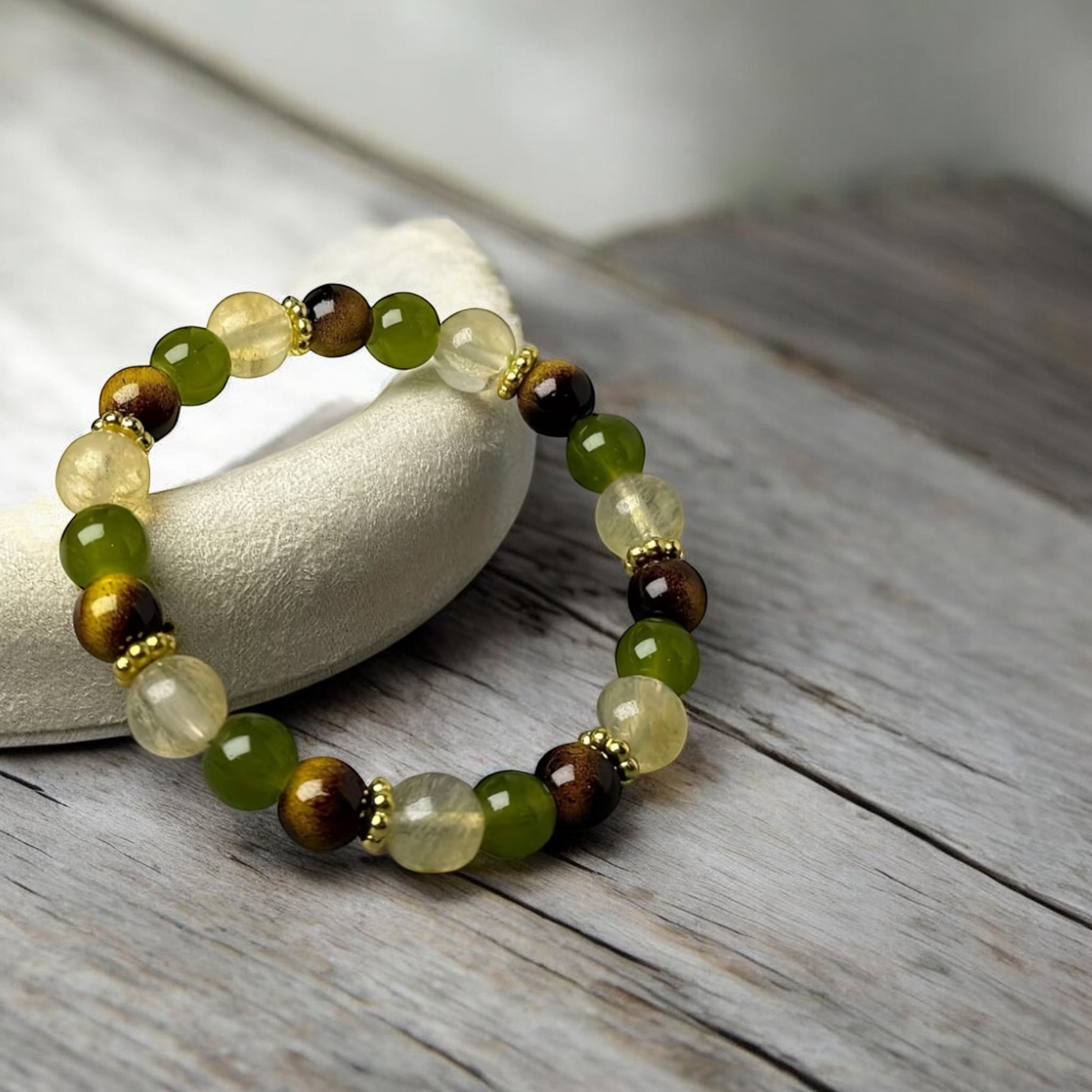 Beaded bracelet with green and brown stones on a wooden surface