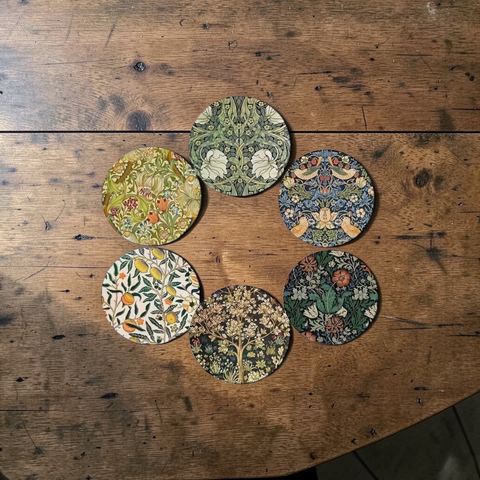 Set of six floral coasters on a wooden surface