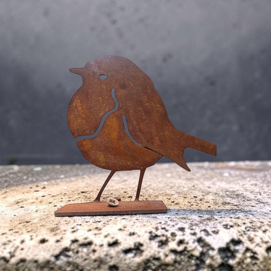 Rust-colored metal bird sculpture on a textured surface with a gray background