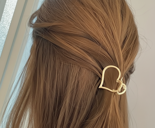 Gold hair clip in a person's brown hair with a neutral background