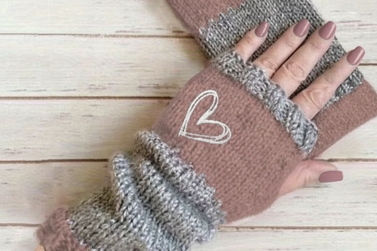 Pair of brown and gray fingerless gloves with a heart design on a wooden surface