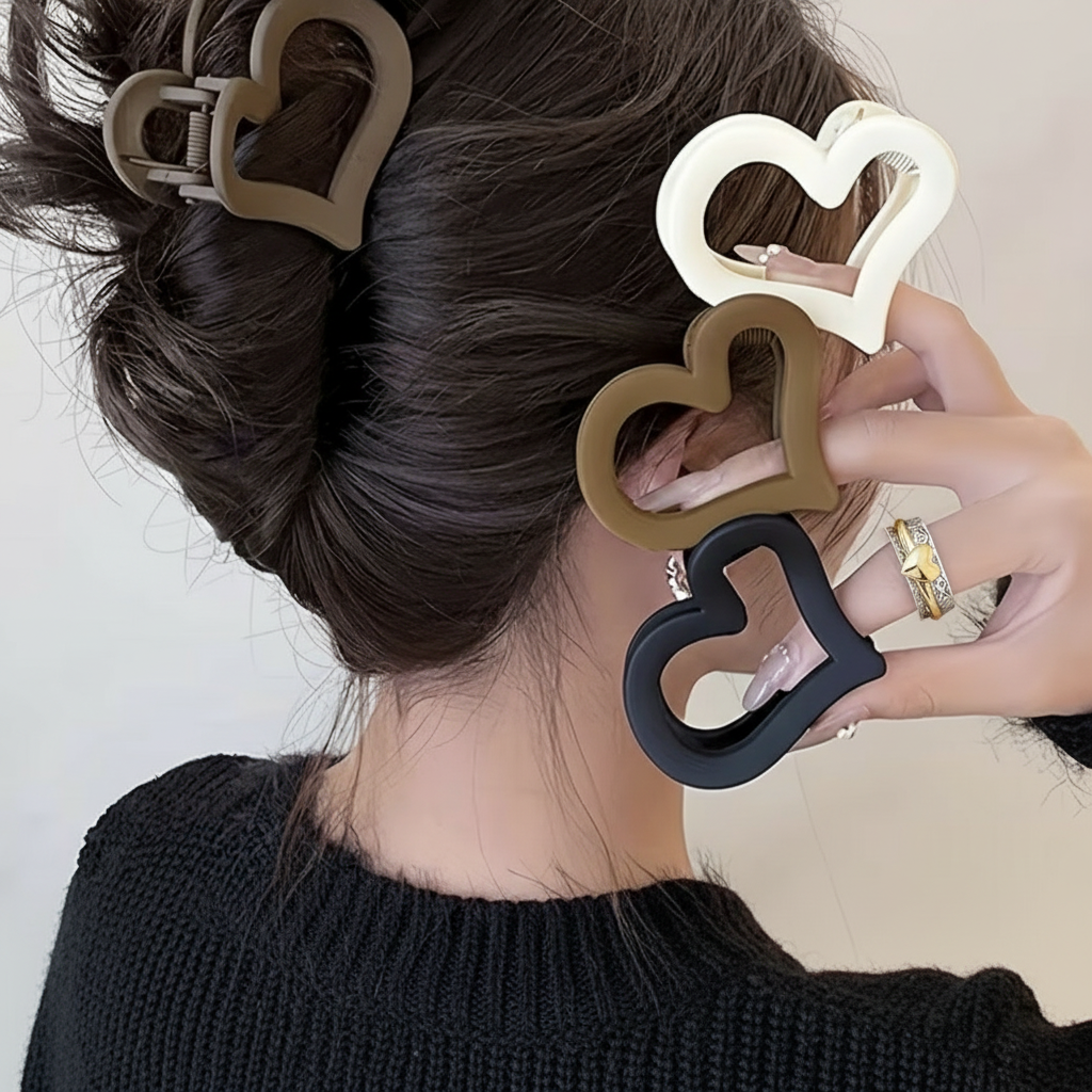 Heart-shaped hair clips in various colors held by a person with dark hair.